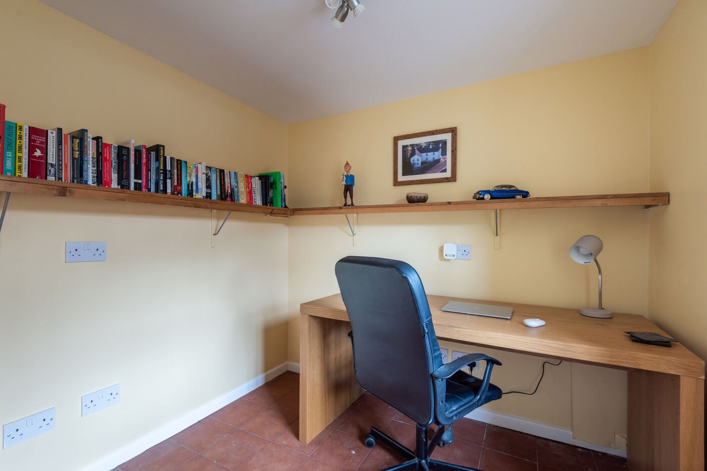 Private study with a large oak desk, bookshelves and a tiled floor